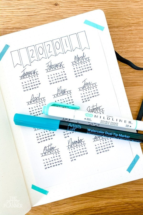 Printable calendar page in a journal with teal markers laying on top